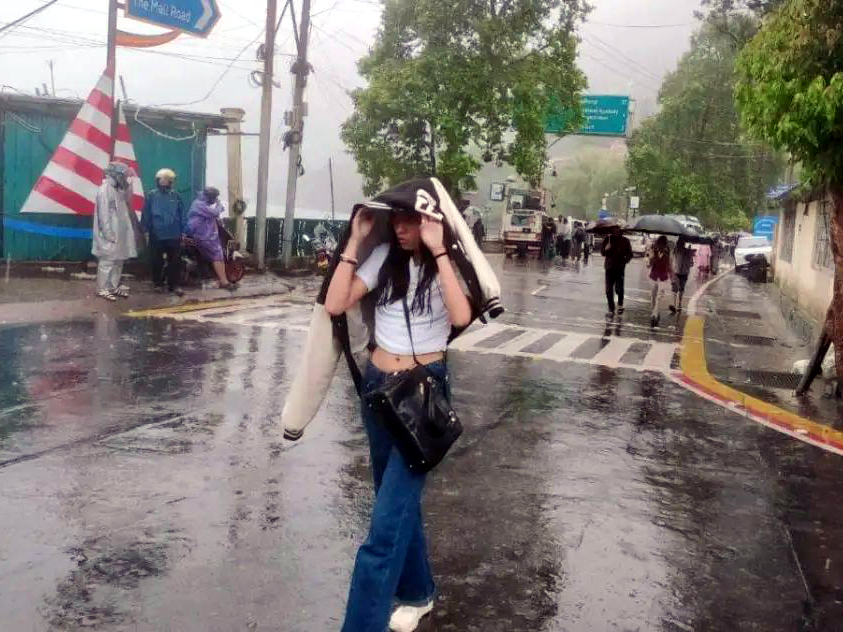 नगर में बारिश के दौरान बचकर निकलती युवती।