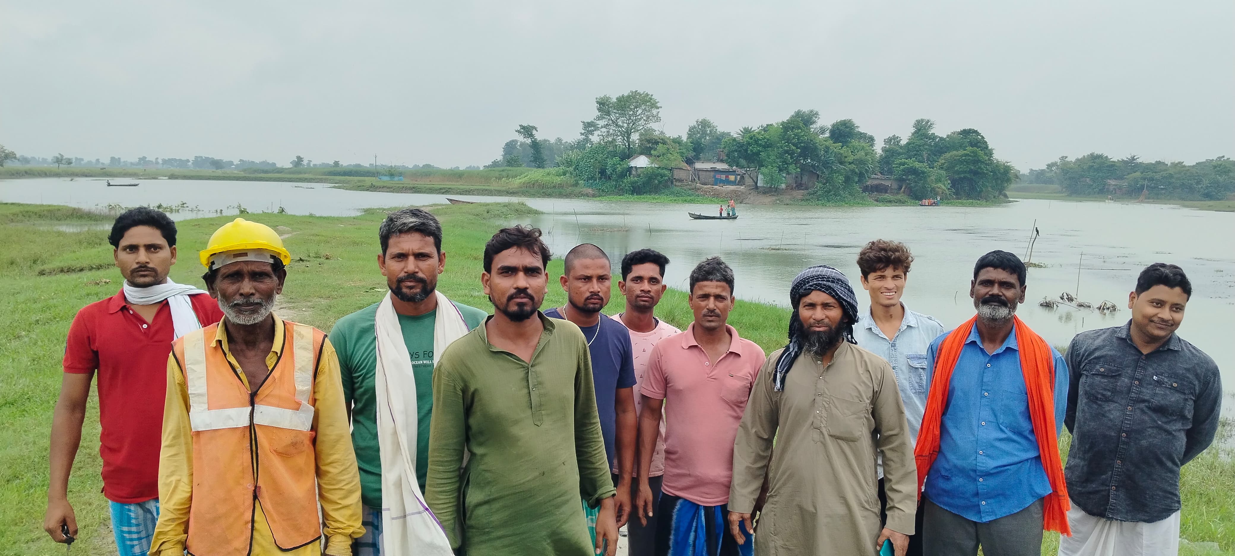 टापू नुमा गांव के सामने नदी किनारे खड़े ग्रामीण