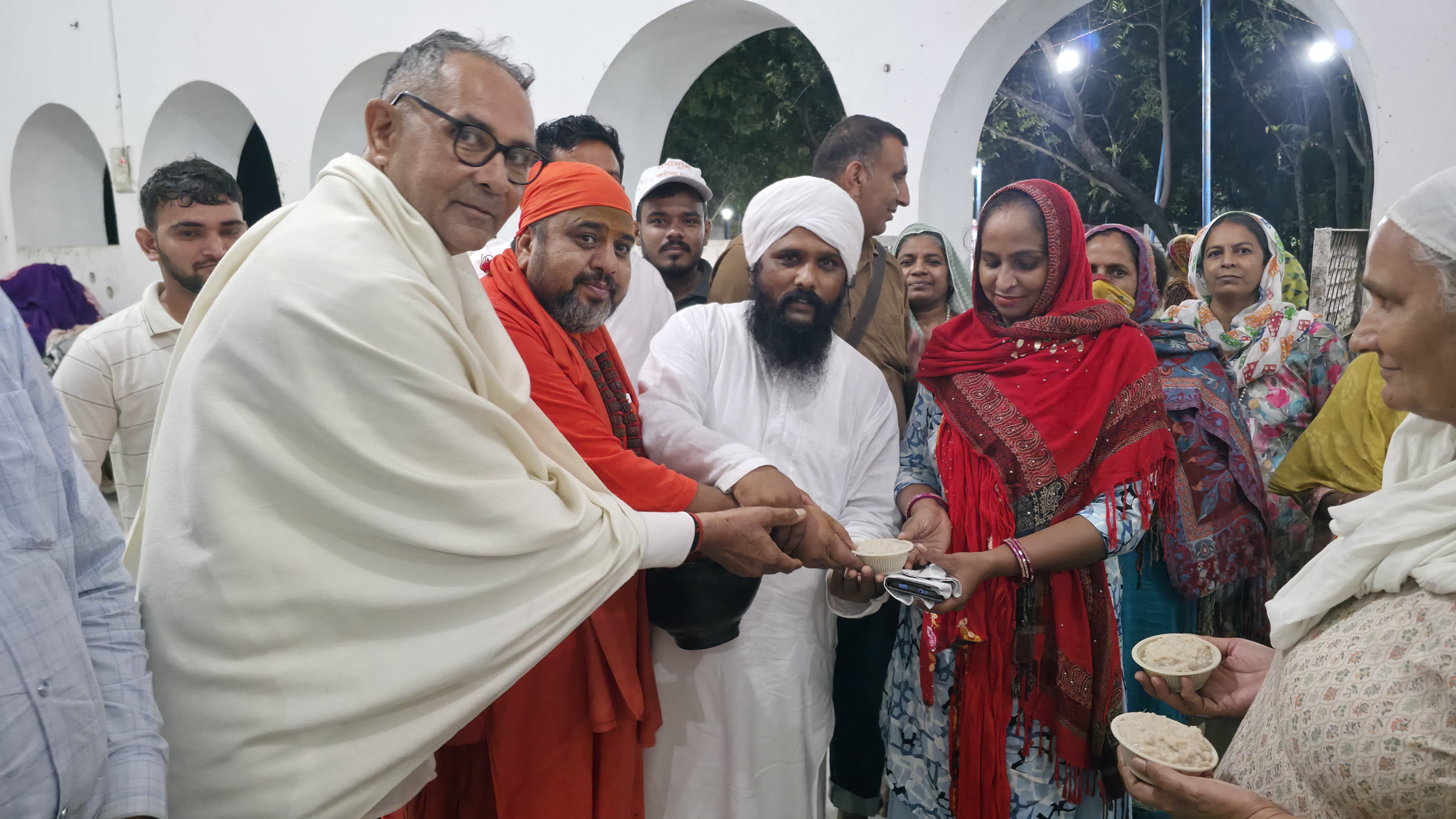 महंत राजेंद्र दास से स्वास्थ्य लाभ के लिए उपचारित खीर का प्रसाद ग्रहण करते लोग।