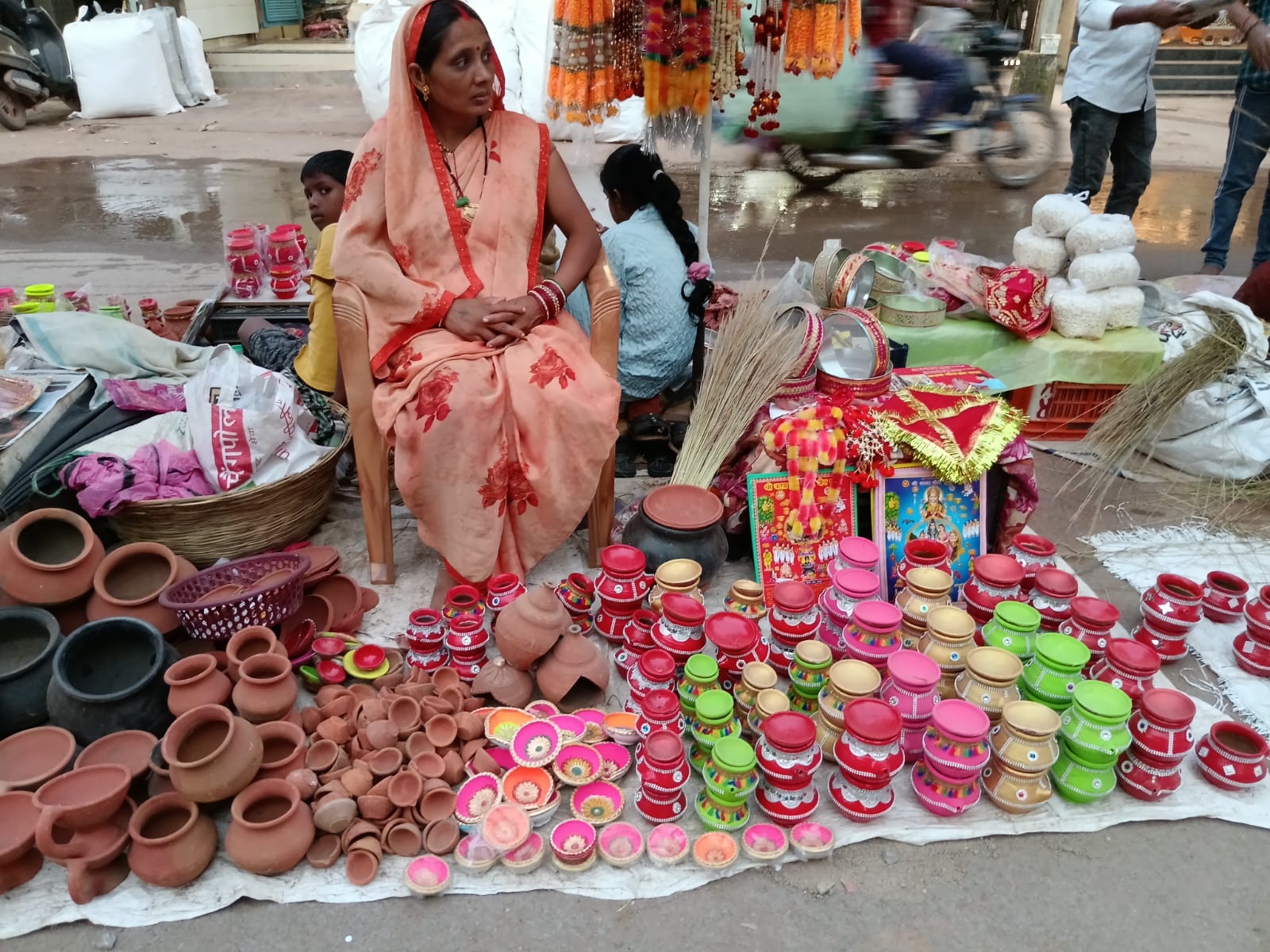 करवा चौथ के लिए मिट्टी के करवे, सजावटी सामान बेंचती हुई महिला।