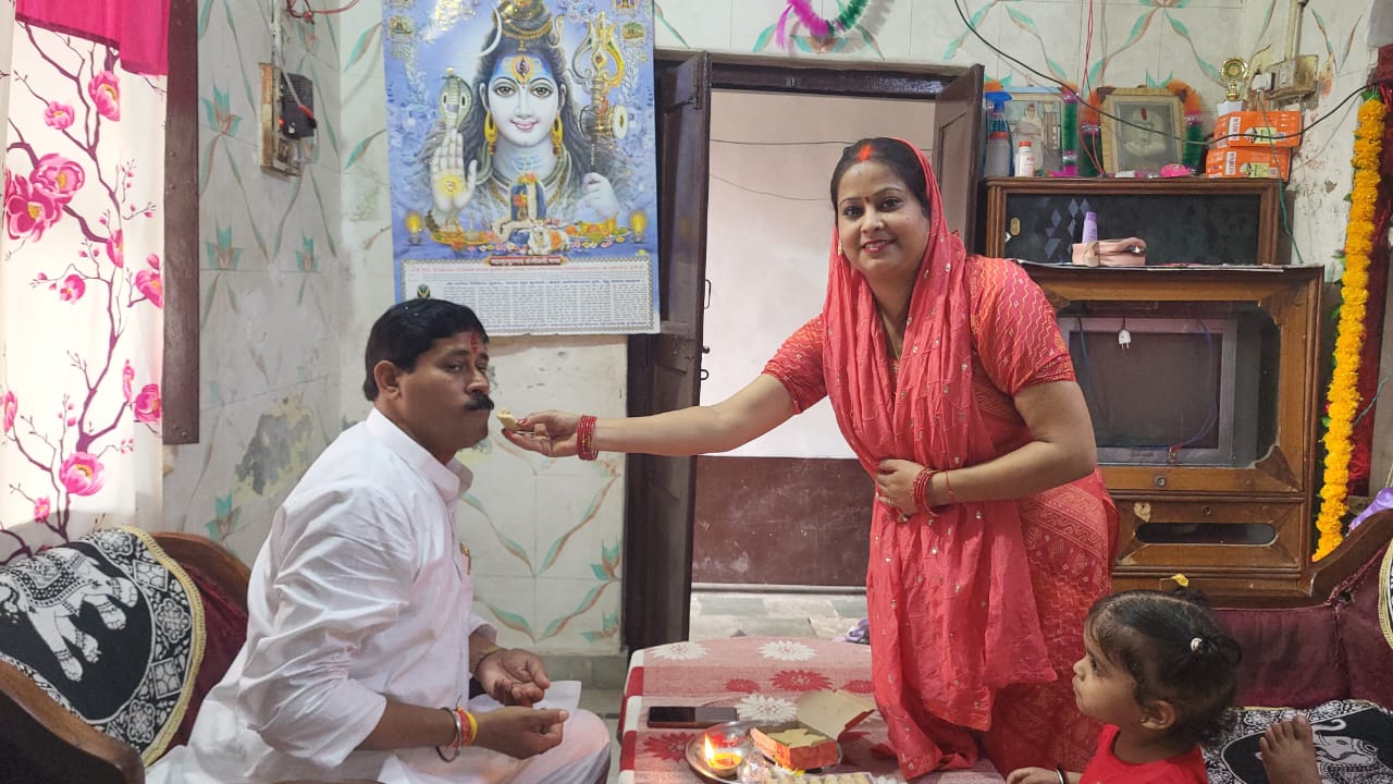 भैया दूज पर बहने भाई को मिठाई खिलते हुए