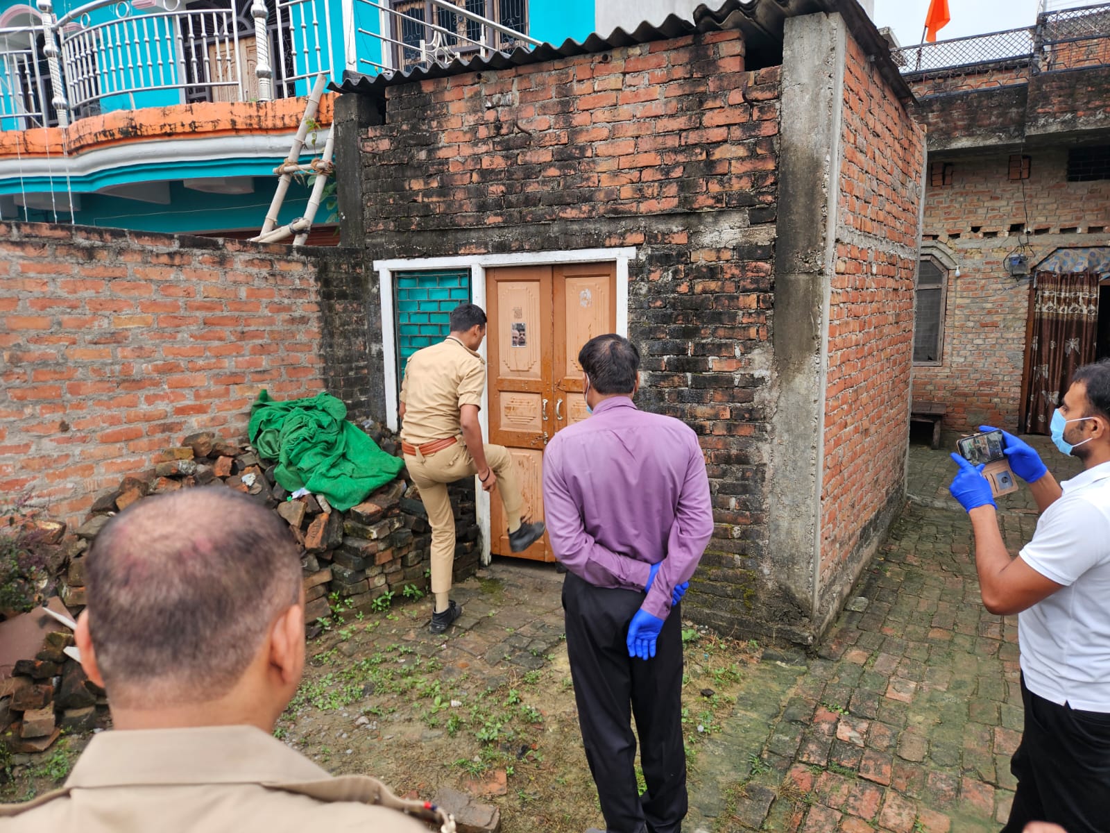 मृतक के घर दरवाजा तोड़ती पुलिस मृतक के घर दरवाजा तोड़ती पुलिस