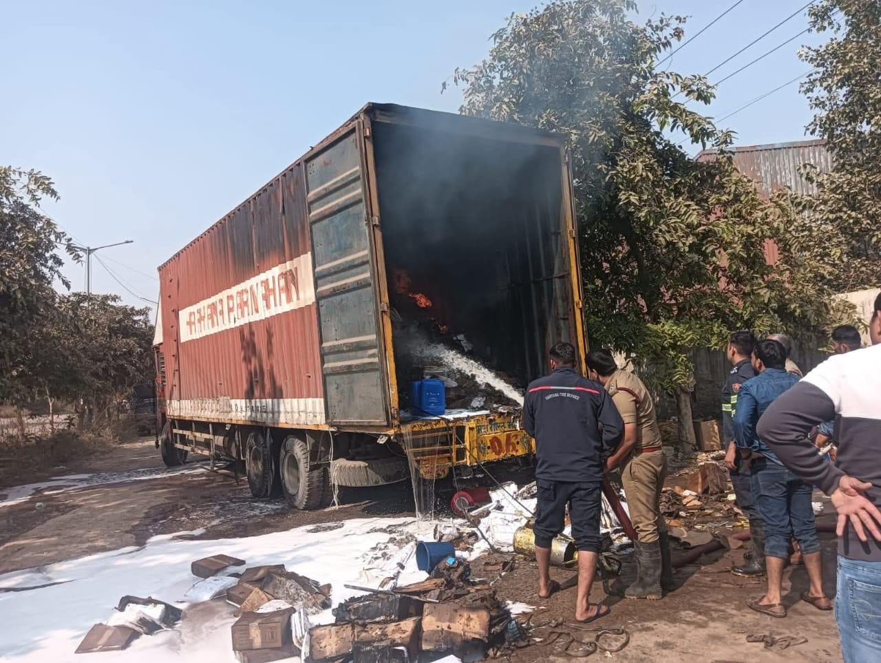 बैट्रियों से भरे कंटेनर में लगी आग को बुझाते हुए दमकल कर्मी।