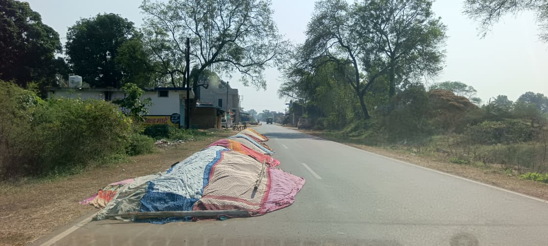 सड़क पर इस तरह से धान सुखा रहे ग्रामीण।