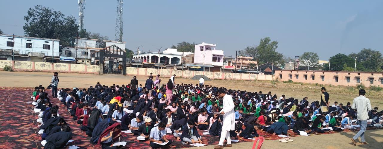 खुले मैदान में बैठे प्रतियोगी