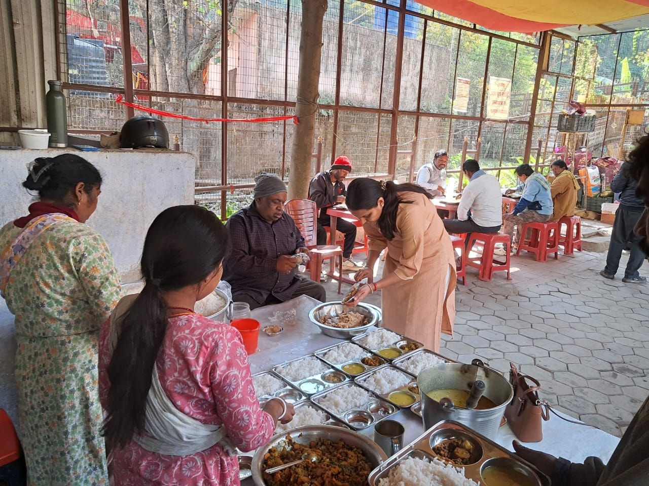 केंद्र की ओर से भोजन परोसती महिलाएं और अन्य