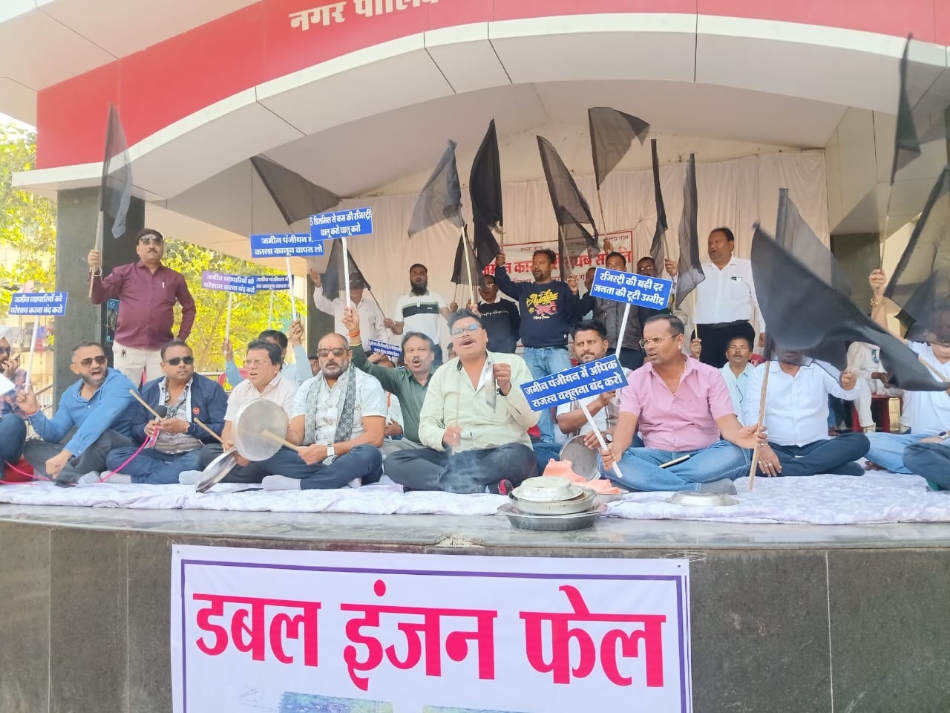 शहर के गांधी मैदान में थाली बजाकर एवं काला झंडा लहराकर विरोध प्रदर्शन करते हुए जमीन कारोबारी.