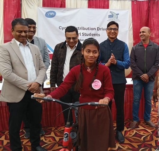 साइकिल प्रदान करते हुए अधिकारी और प्राप्त करती छात्रा