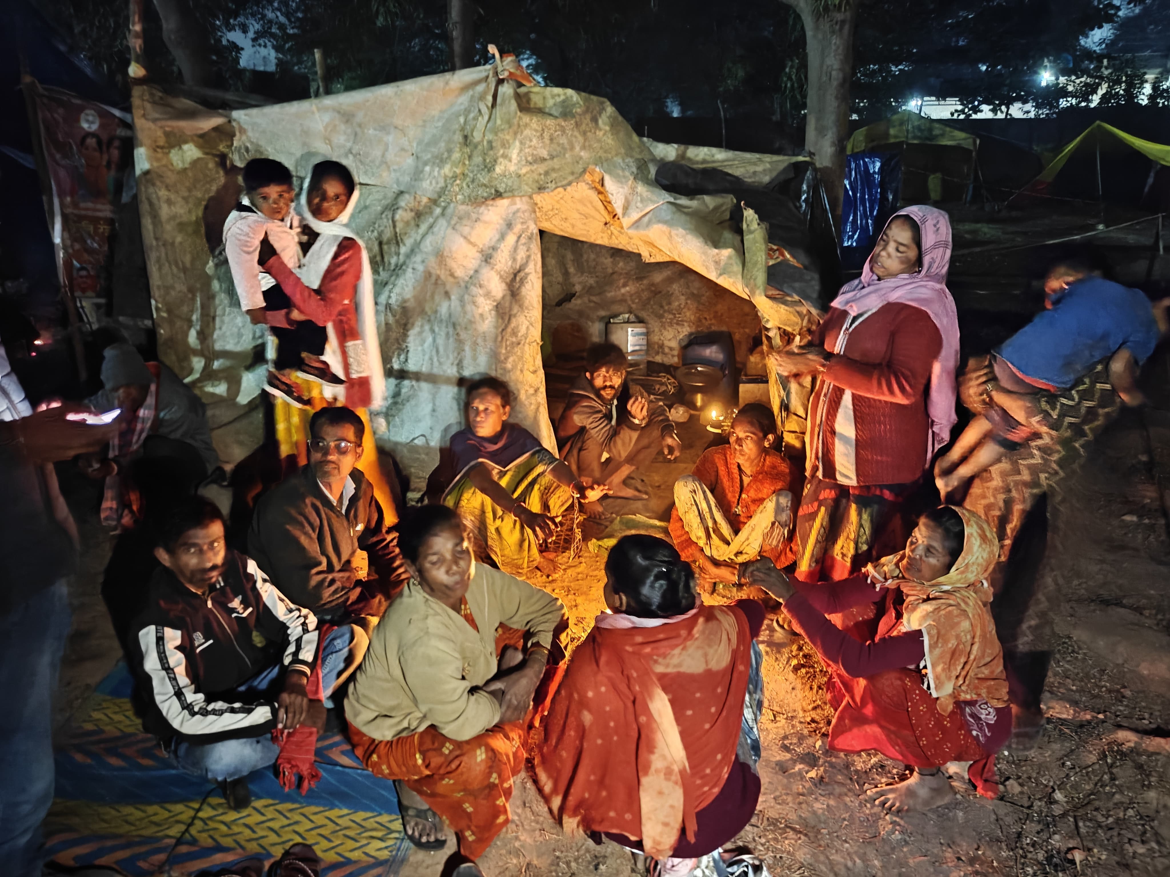 कड़ाके की इस ठंड में परिवार तंबू के पास एक साथ बैठकर अलाव का सहारा लेते हुए।
