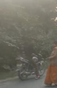 बाइक पर बैठा युवक और सड़क पर खड़ी पीड़ित महिला
