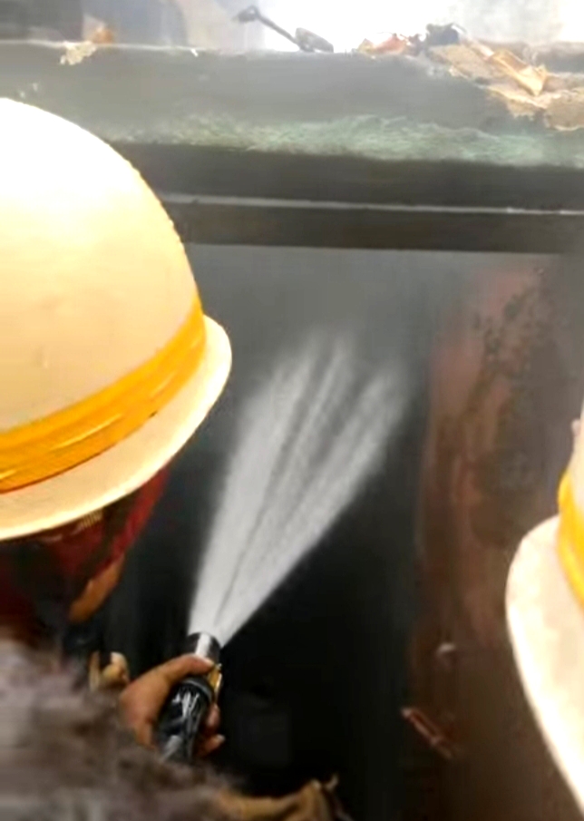 इंदा शक्ति भवन के सामने लगी आग पर काबू पाते दमकल कर्मी।