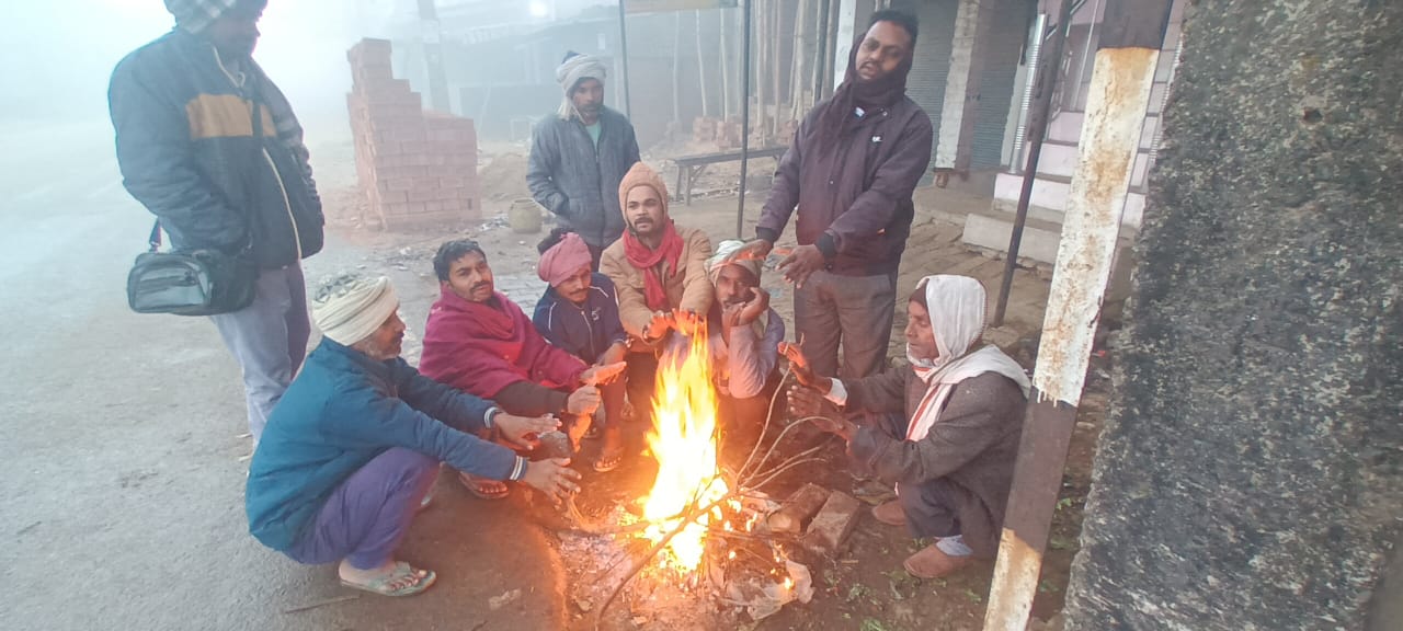ठंड से बचने के लिय अलाव के पास बैठे ग्रामीण