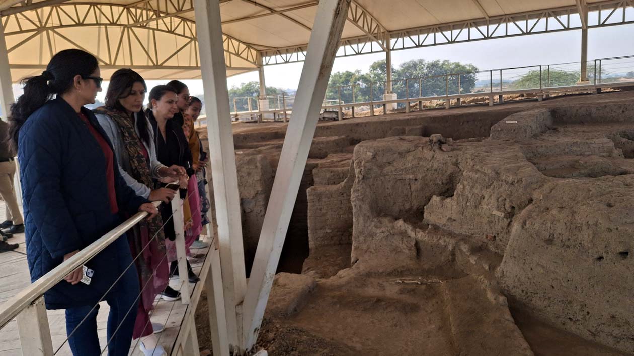 राखीगढ़ी के टीले तीन पर खुदाई के दौरान निकले मकानों को देखते पर्यटक।