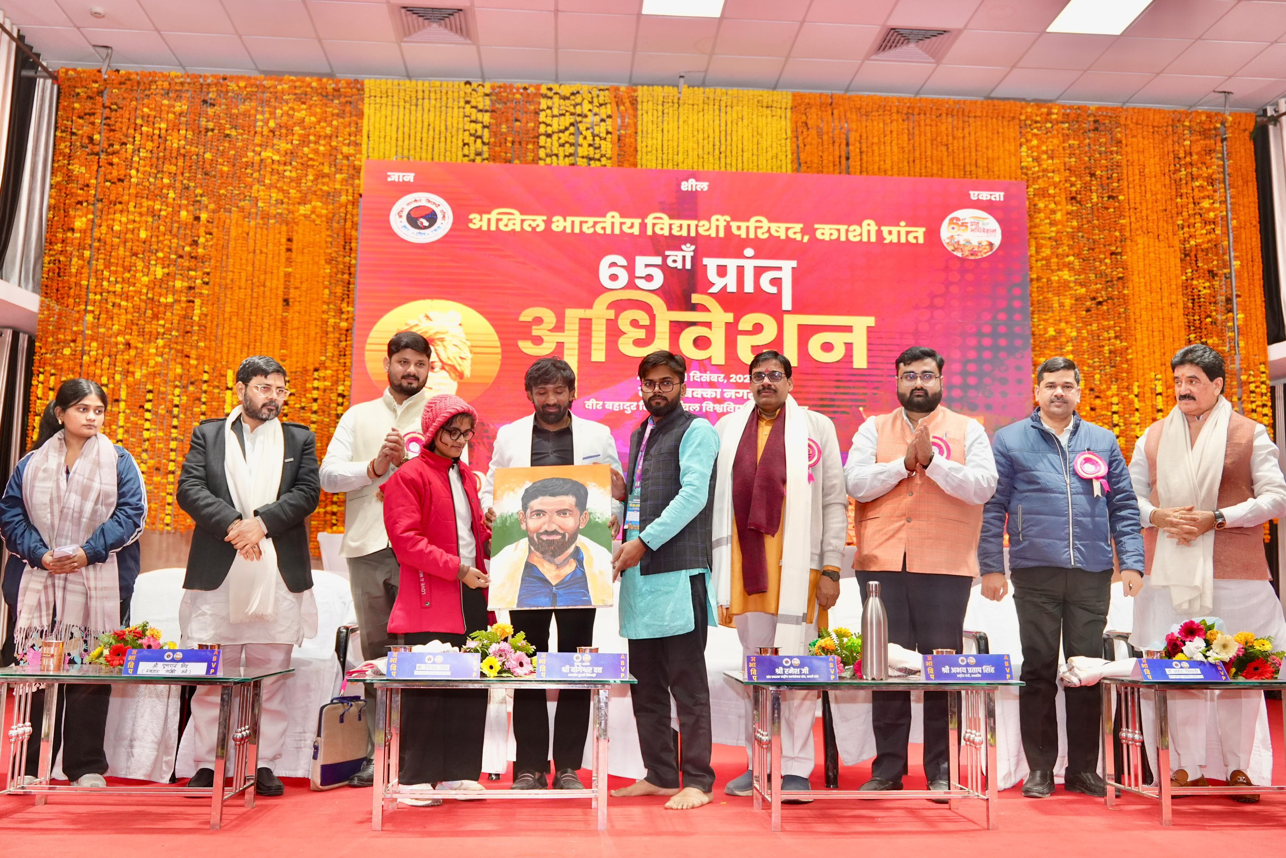 पूर्वांचल विश्वविद्यालय में चल रही अभाविप सम्मेलन में अभाविप की कला मंच की कार्यकर्ता  द्वारा पद्मश्री से सम्मानित योगेश्वर दत्त का चित्र बनाकर भेट करते हुए सम्मानित करते हुए अतिथि लोग