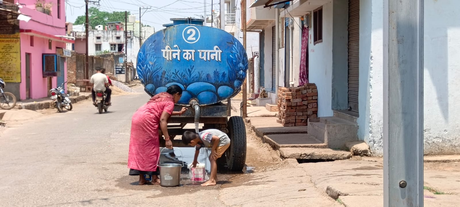 टैंकर से पानी भरती हुई महिला। टैंकर से पानी भरती हुई महिला।