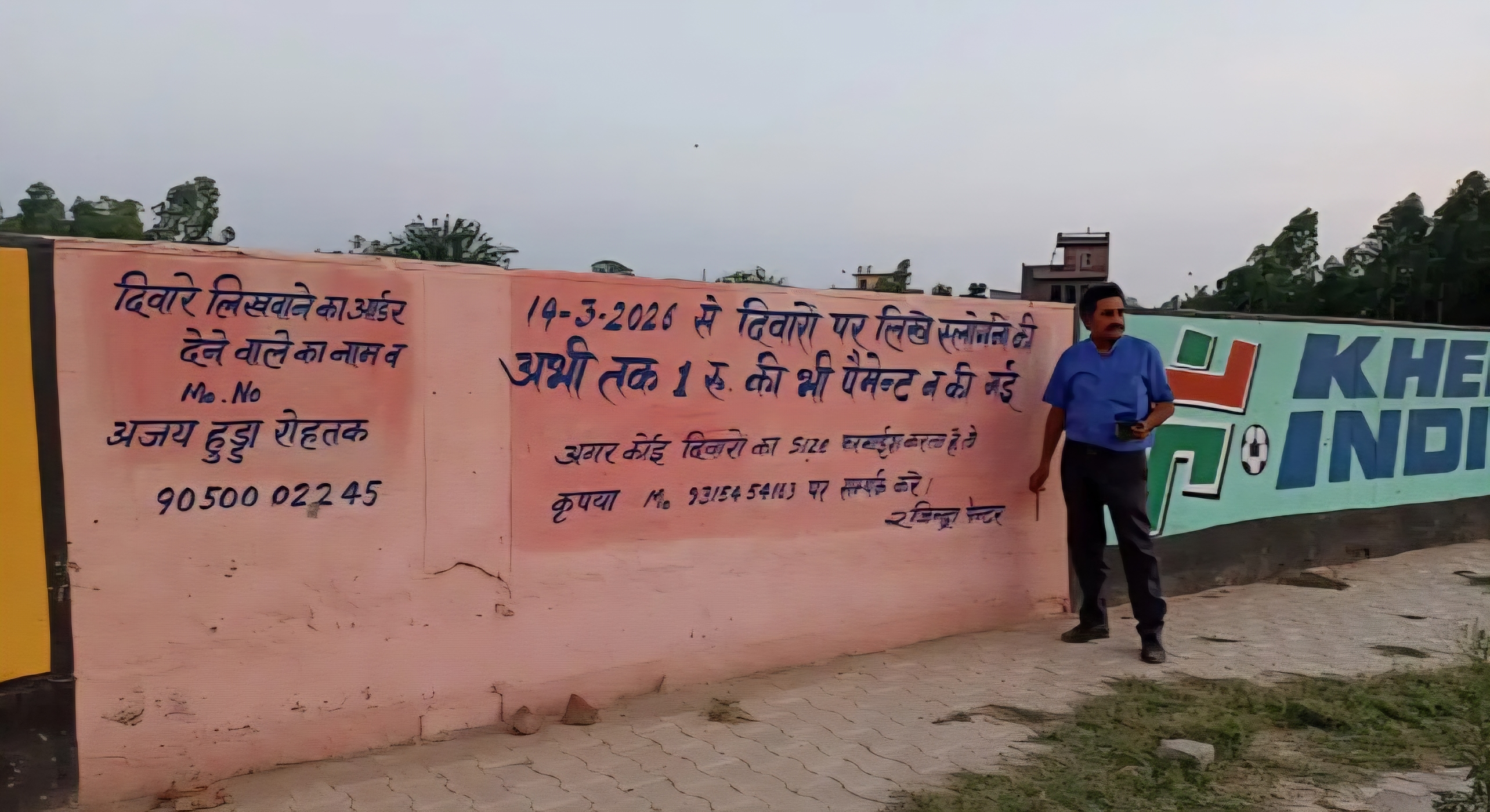 दीवार पर लिख कर बकाया भुगतान न मिलने का विरोध जताते हुए पे पेंटर