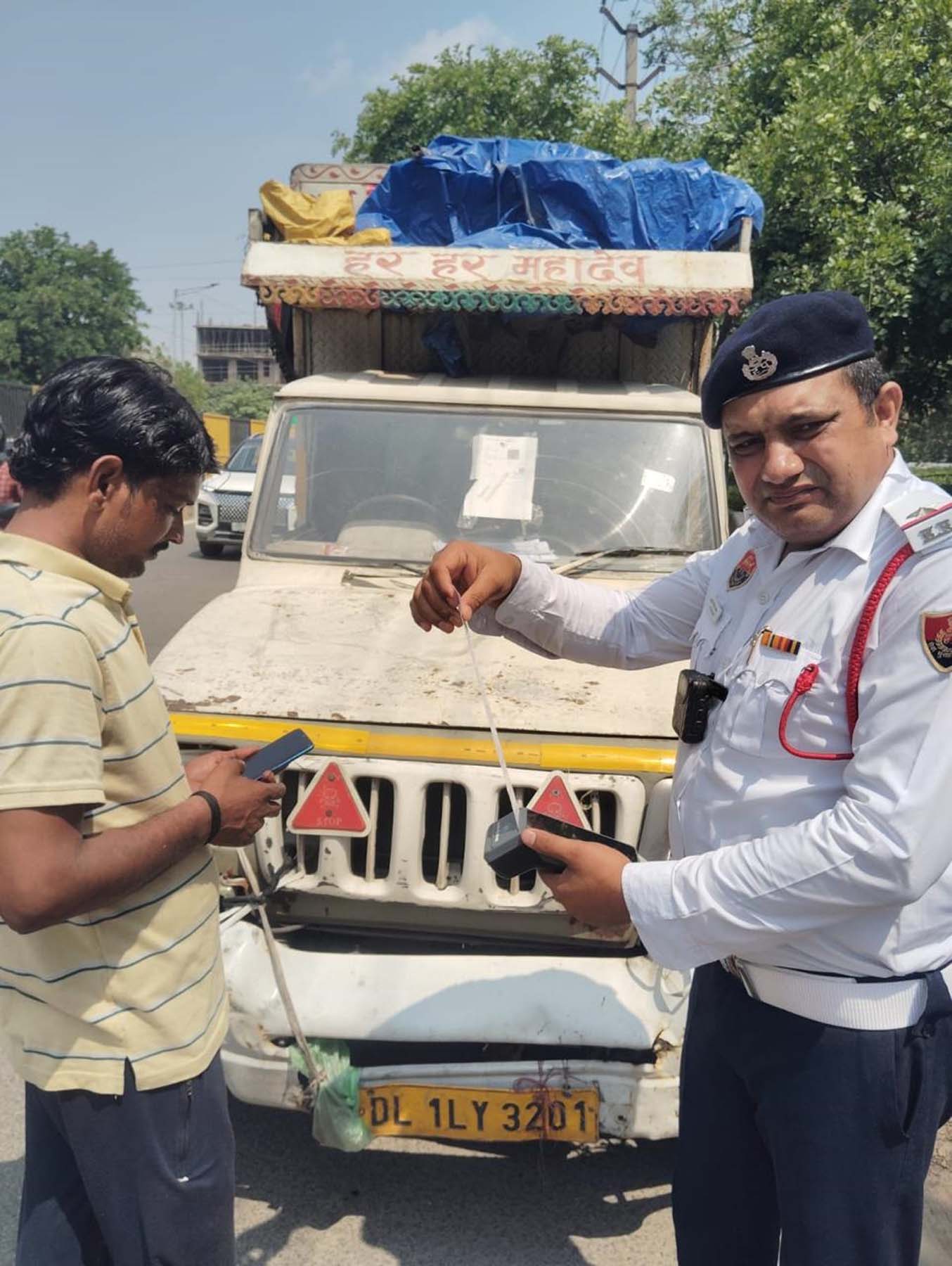 गुरुग्राम में नौ लाख रुपये चालान बकाया होने पर पिकअप का चालान काटते यातायात पुलिस अधिकारी।