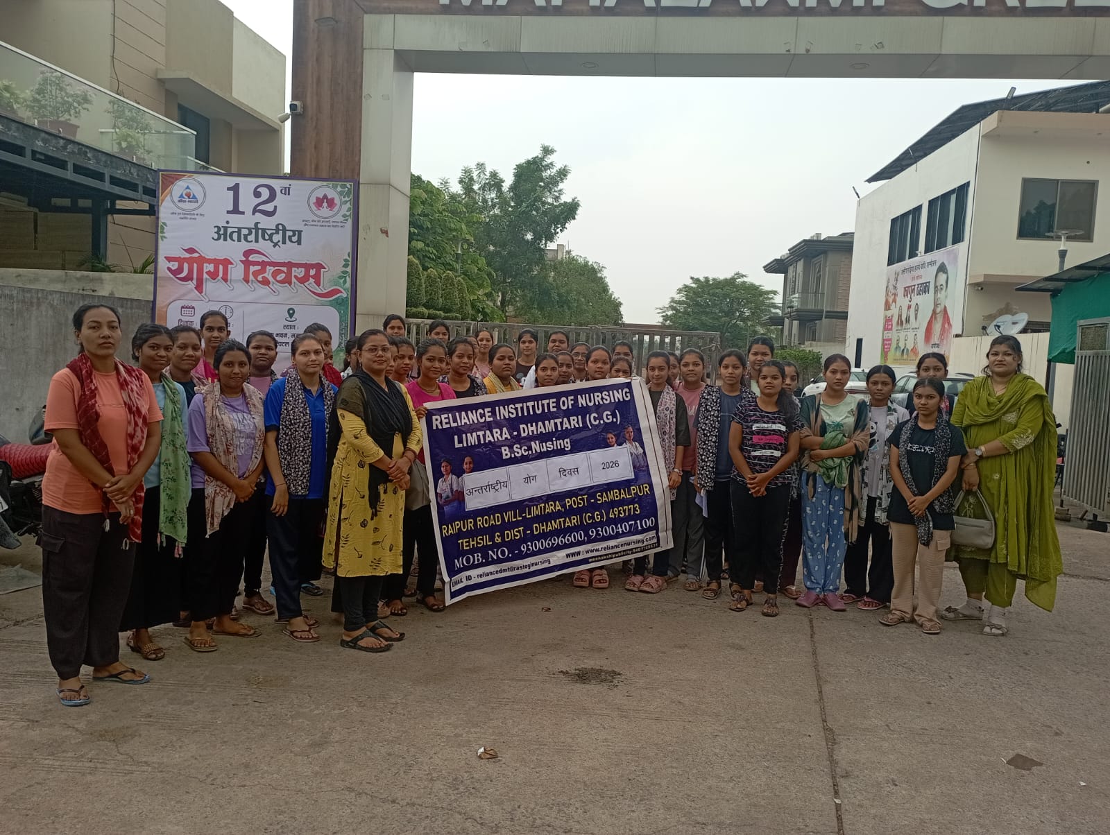 समूह में खड़े हुए कॉलेज के विद्यार्थी व अन्य लोग।