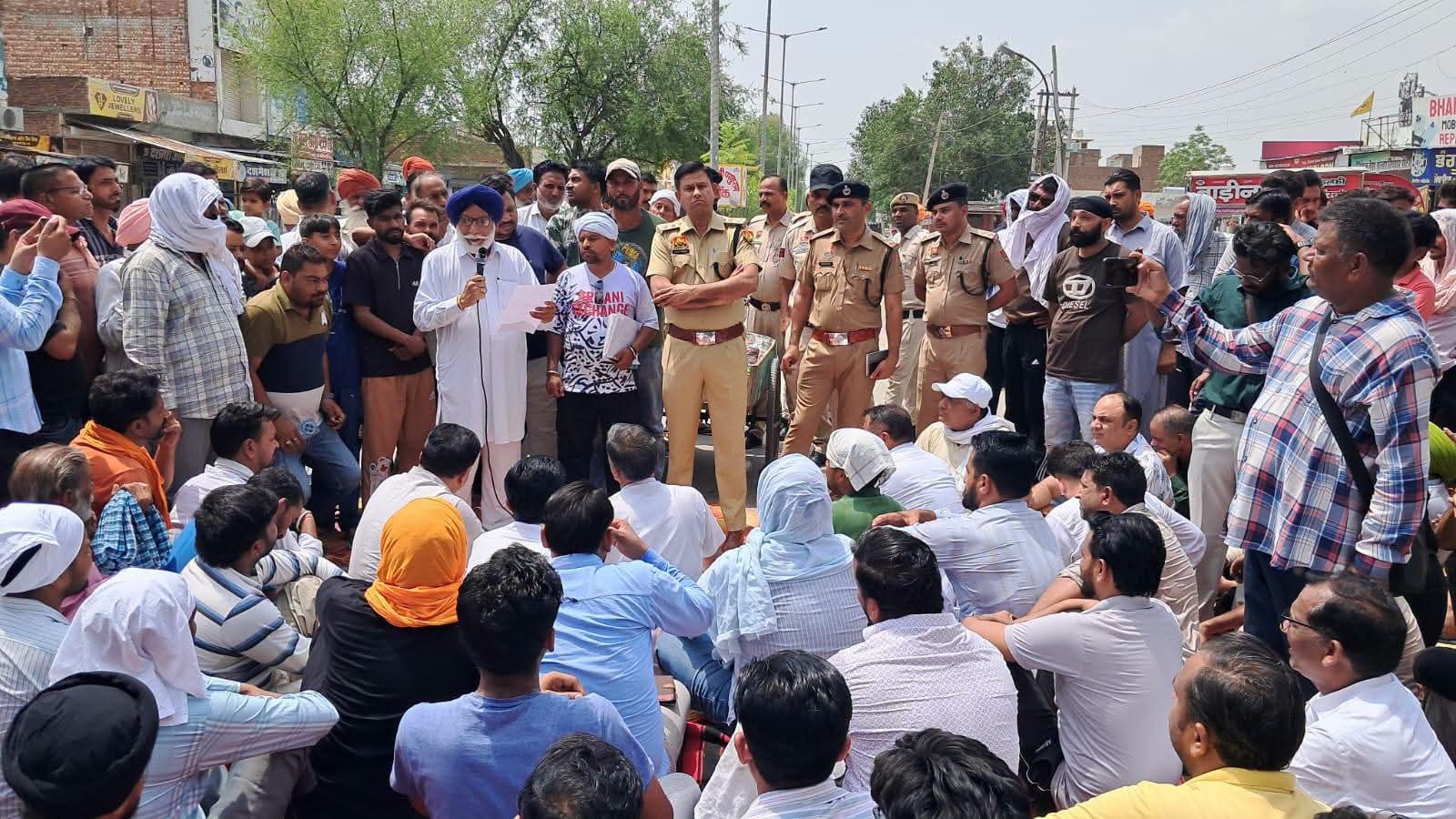 पुलिस के खिलाफ धरना देते लोग।