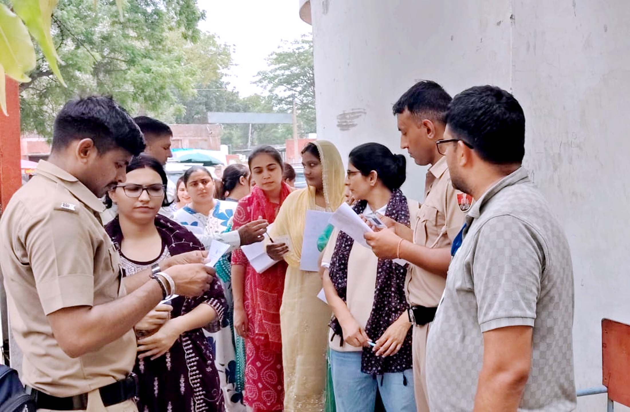 परीक्षा केंद्र में जाने से पहले परीक्षार्थियों के रोल नंबर की जांच करते हुए पुलिसकर्मी।