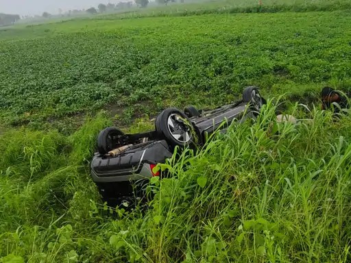 खेत में पलटी पड़ी कार।