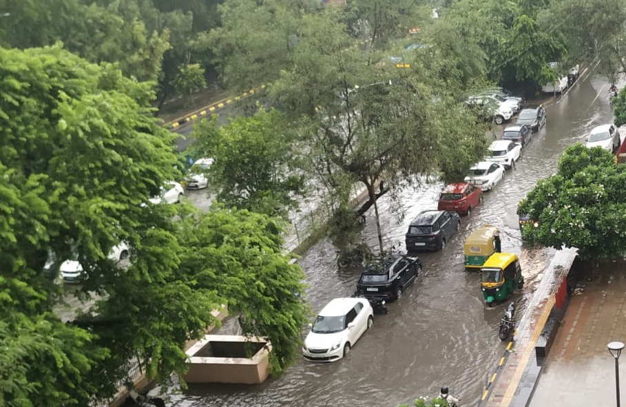 आजादपुर मेट्रो स्टेशन के बाहर जलभराव से वाहन गुजरते हुए।